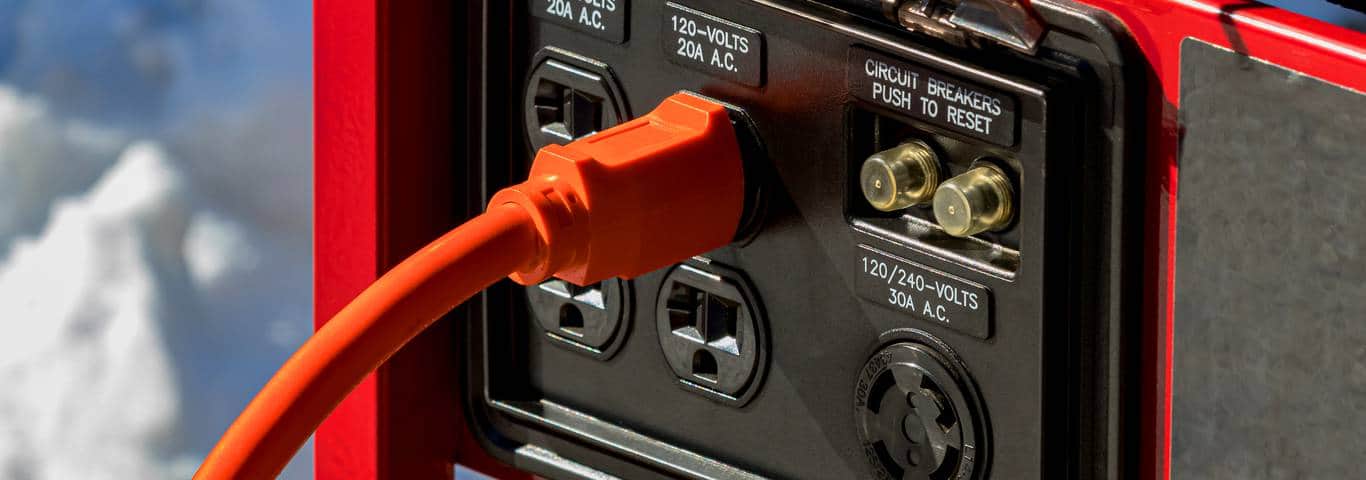 Pomarańczowy przewód podłączony do agregatu prądotwórczego na zewnątrz domu