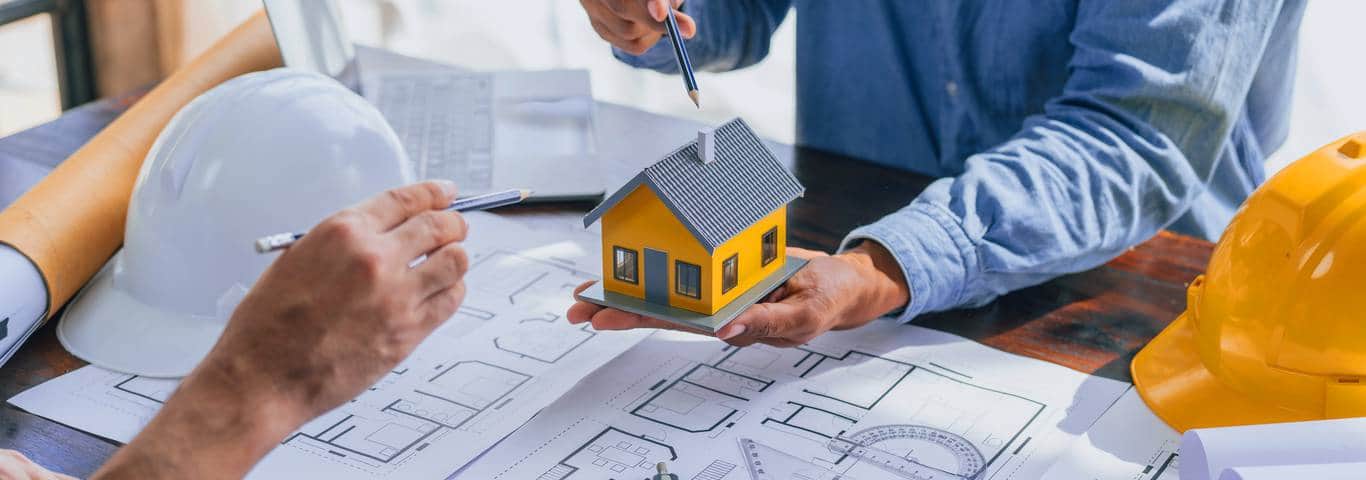 Architekt omawia projekt elewacji na przykładzie modelu domu i rysunków technicznych