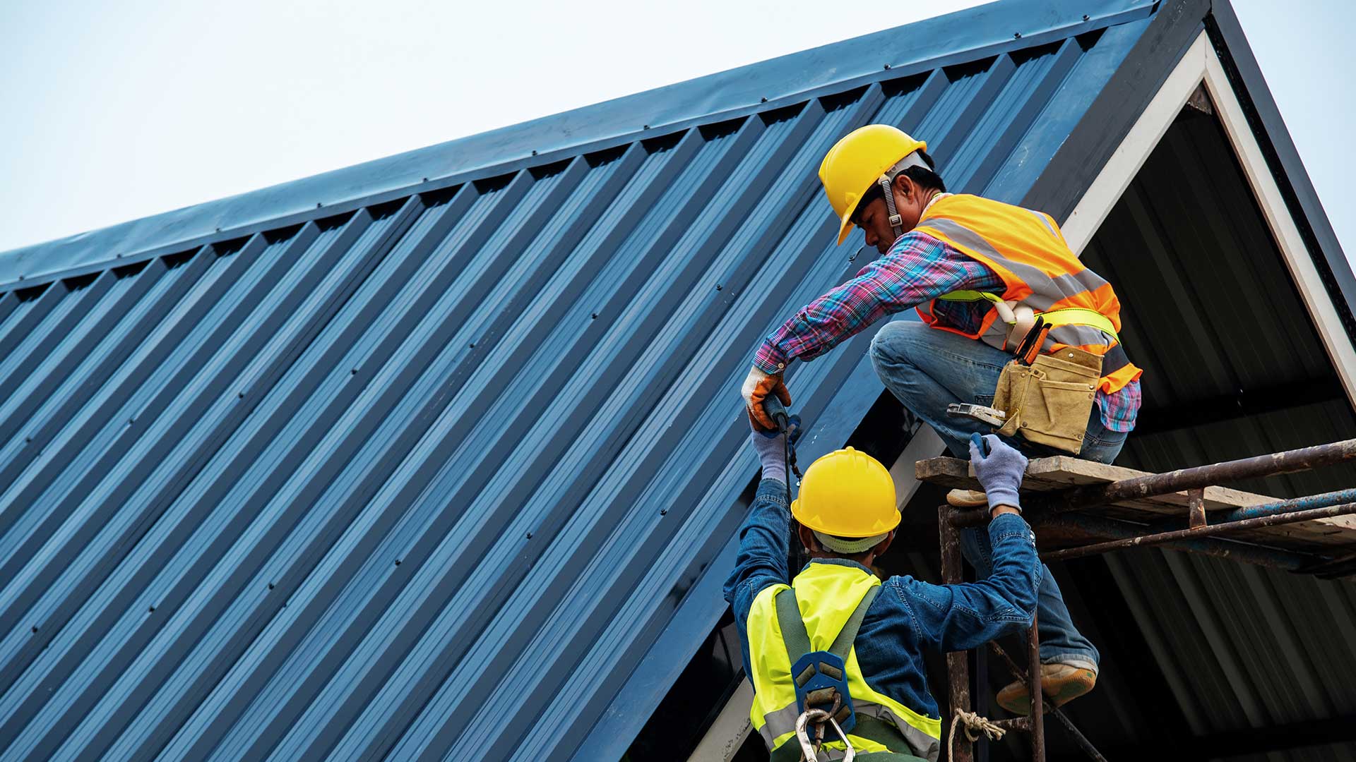 dekarze montują blachę trapezową na dachu nowego budynku