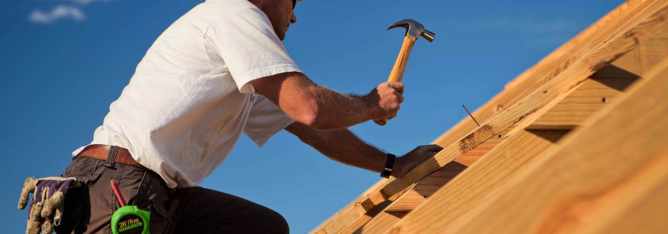 fachowiec przybija deski w trakcie deskowania dachu