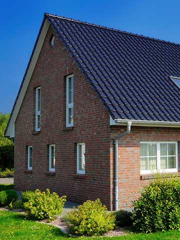 niewielki dom jednopiętrowy z cegły z dachem dwuspadowym