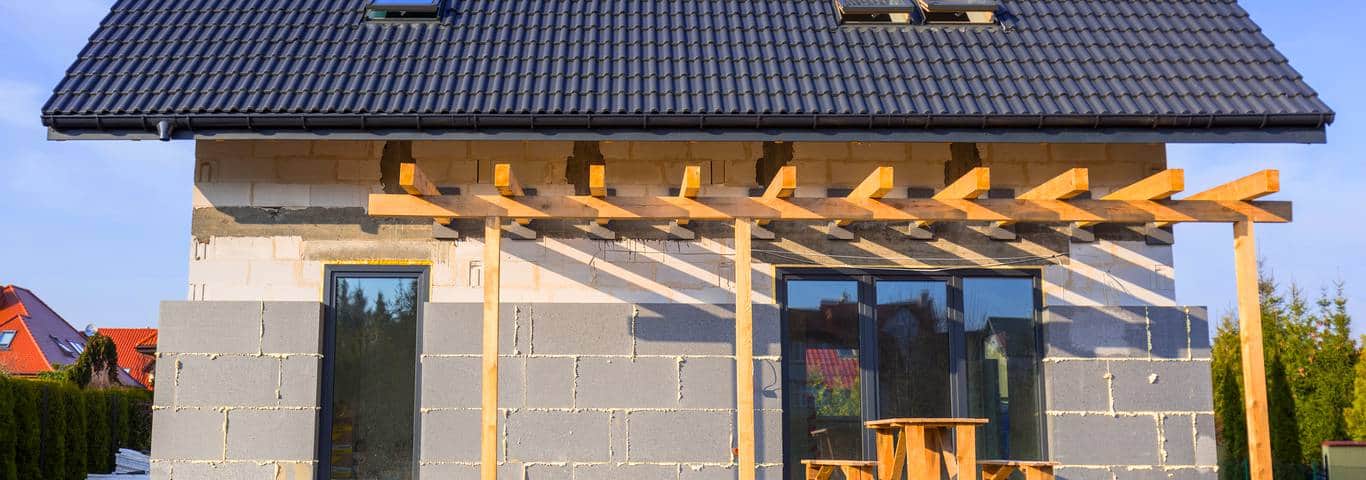 dom w budowie z warstwą styropianu do ocieplenia domu na elewacji i czarną blachodachówką