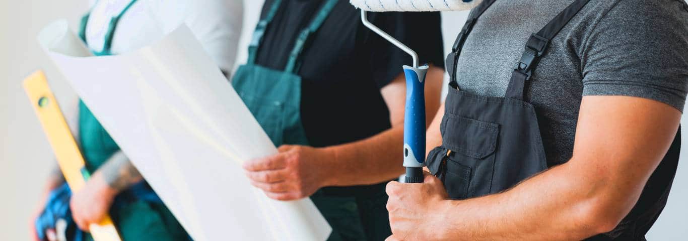 zbliżenie na wałek malarski i akcesoria malarskie trzymane w rękach malarzy