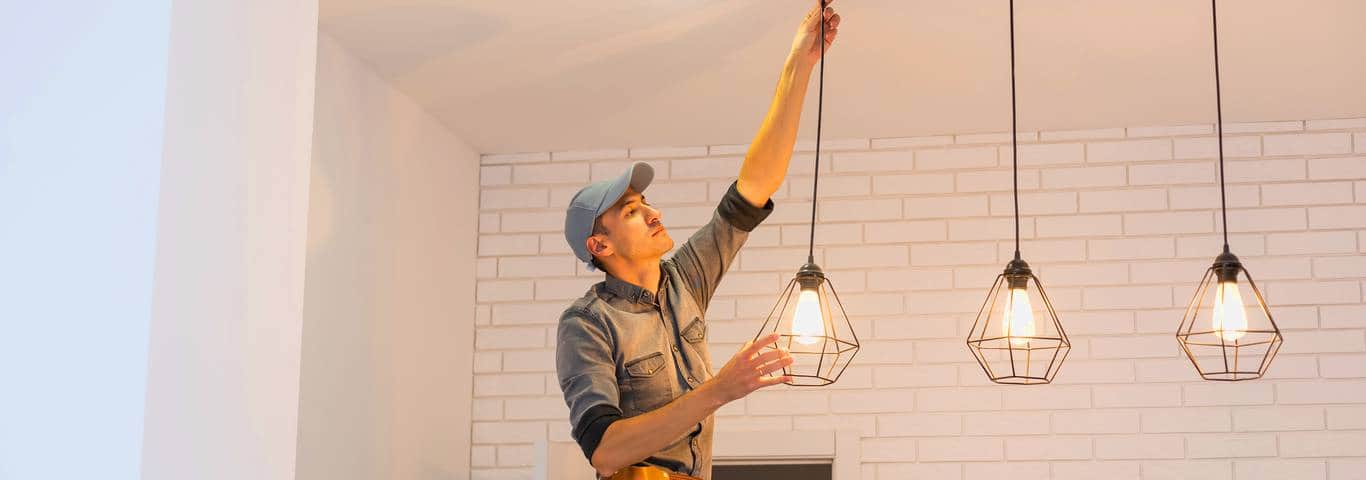 Elektryk montuje lampy wiszące w kuchni