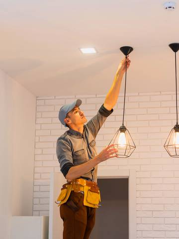 elektryk instaluje lampy elektryczne w kuchni