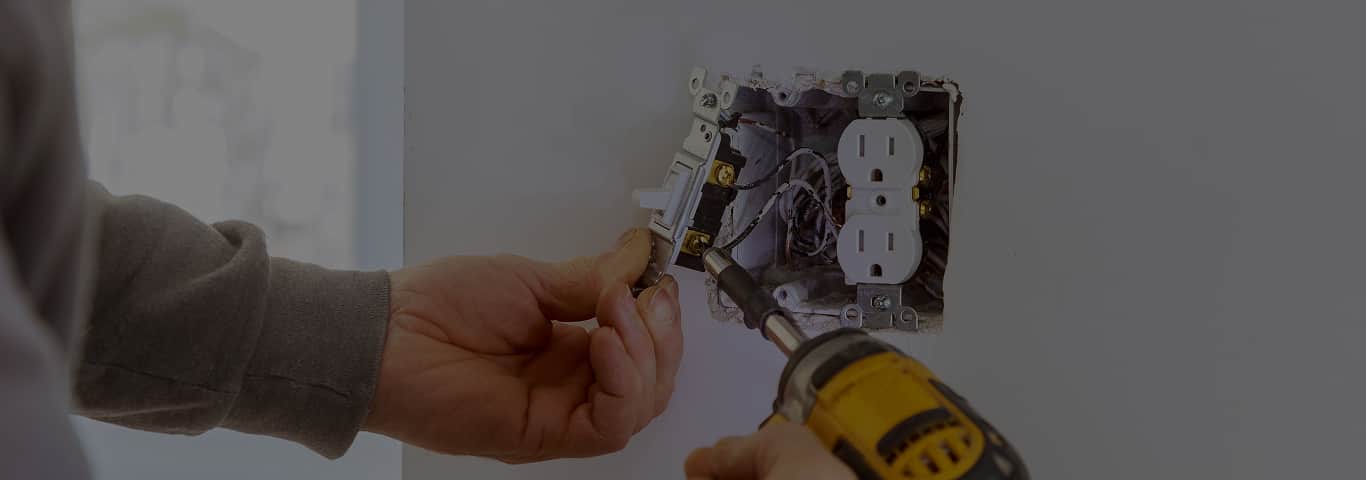 Fachowiec montuje gniazdko elektryczne w ścianie – przykład drobnych prac instalacyjnych