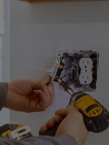 Fachowiec montuje gniazdko elektryczne w ścianie – przykład drobnych prac instalacyjnych