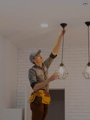 Elektryk montuje lampy sufitowe w stylu loftowym