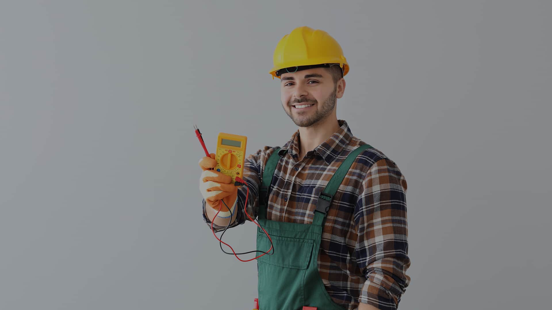 Elektryk trzyma miernik cyfrowy podczas pomiar&oacute;w instalacji elektrycznej