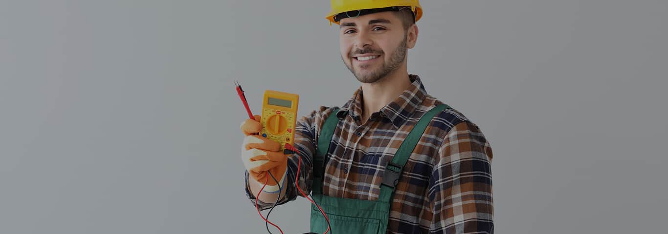 Elektryk trzyma miernik cyfrowy podczas pomiarów instalacji elektrycznej