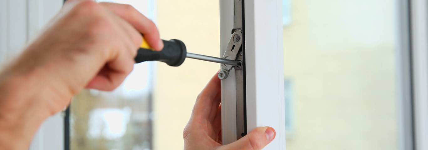 fachowiec reguluje okucia okienne śrubokrętem