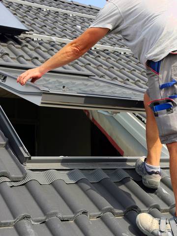 Specjalista montujący okno dachowe na dachu