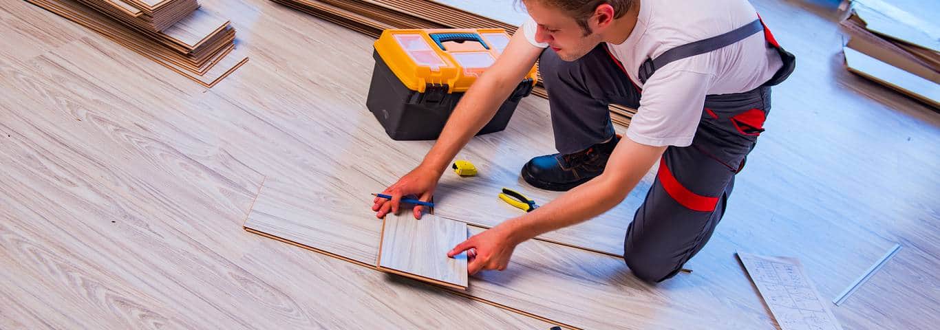 fachowiec układa panele podłogowe przy pomocy narzędzi