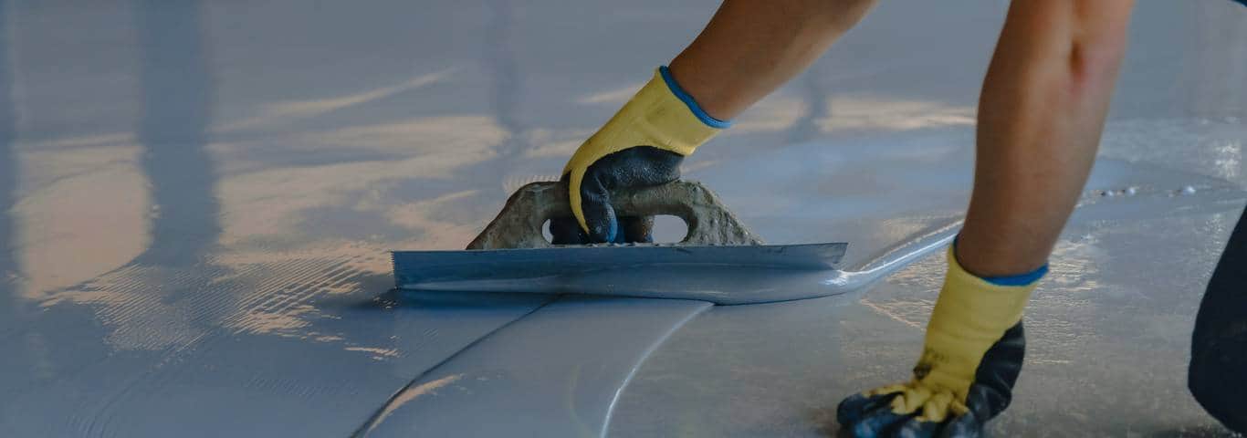 ręka fachowca nakłada posadzkę żywiczną