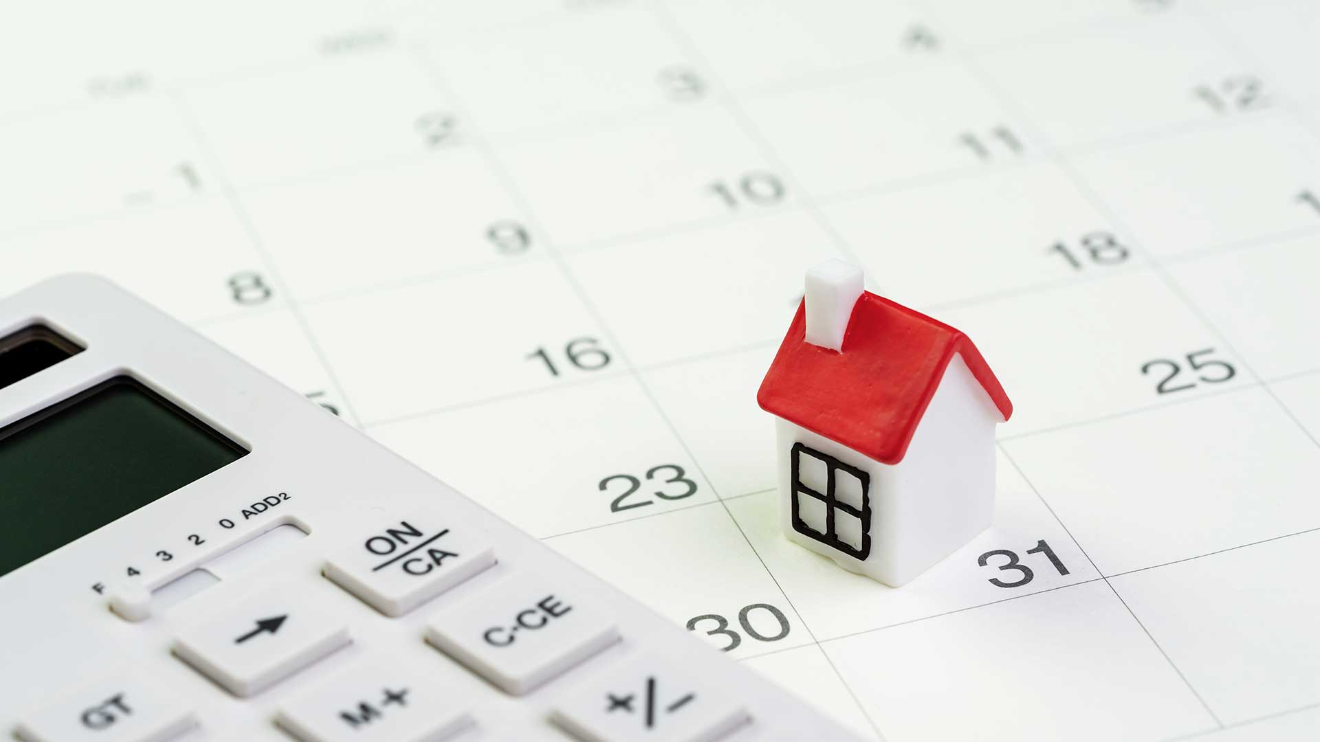 model białego domku z czerwonym dachem i kalkulator leżą na białej kartce kalendarza -  w 2021