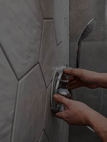 Hydraulik montuje armaturę prysznicową na ścianie w łazience