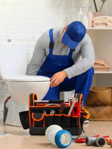 Hydraulik montuje toaletę w łazience – element instalacji kanalizacyjnej