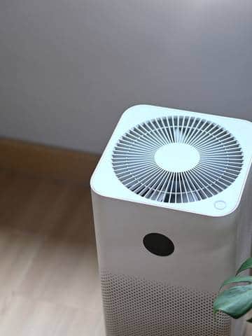 Przenośny klimatyzator ustawiony na drewnianej podłodze w nowoczesnym wnętrzu