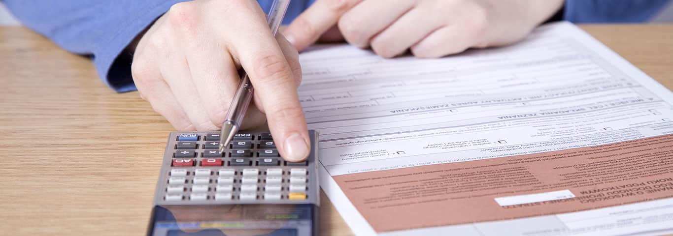 kobieta liczy na kalkulatorze wartość podatku dochodowego