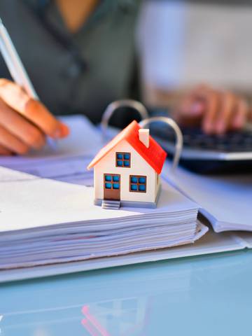 zbliżenie na model domu na dokumentach podatku od sprzedaży nieruchomości