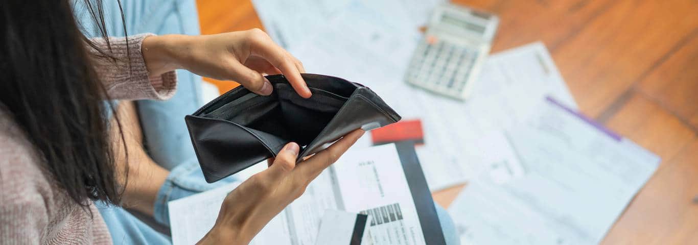 kobieta otwiera pusty portfel nad dokumentami 