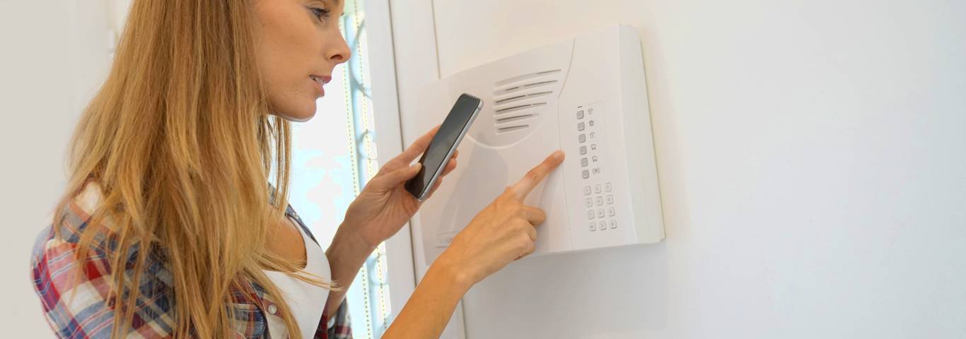 kobieta programuje alarm domowy przed wyjściem z domu