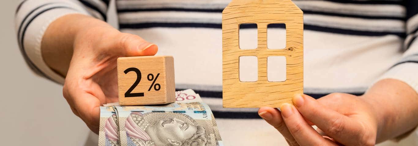 kobieta trzyma w rękach pieniądze z kredytu 2 procent i model domu