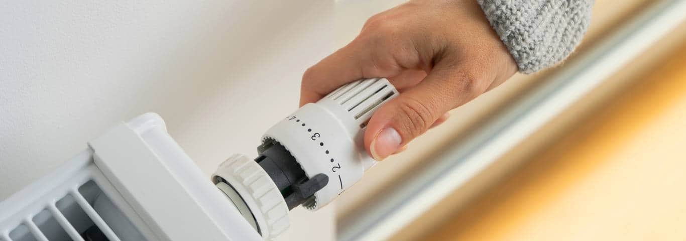 zbliżenie na rękę kobiety ustawiającej termostat grzejnikowy