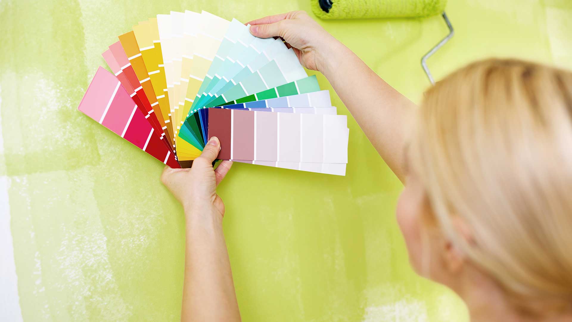 kobieta wybiera kolor farby na ścianę za pomocą próbnika farb