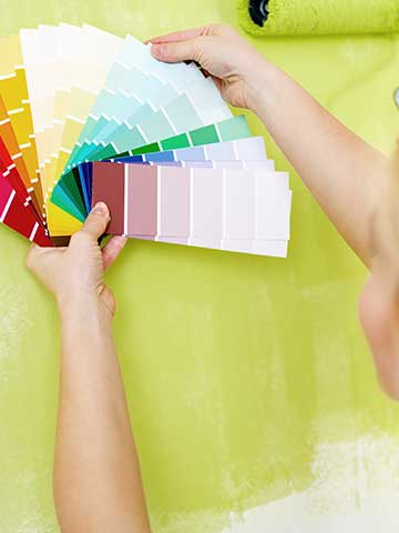kobieta wybiera kolor farby na ścianę za pomocą próbnika farb