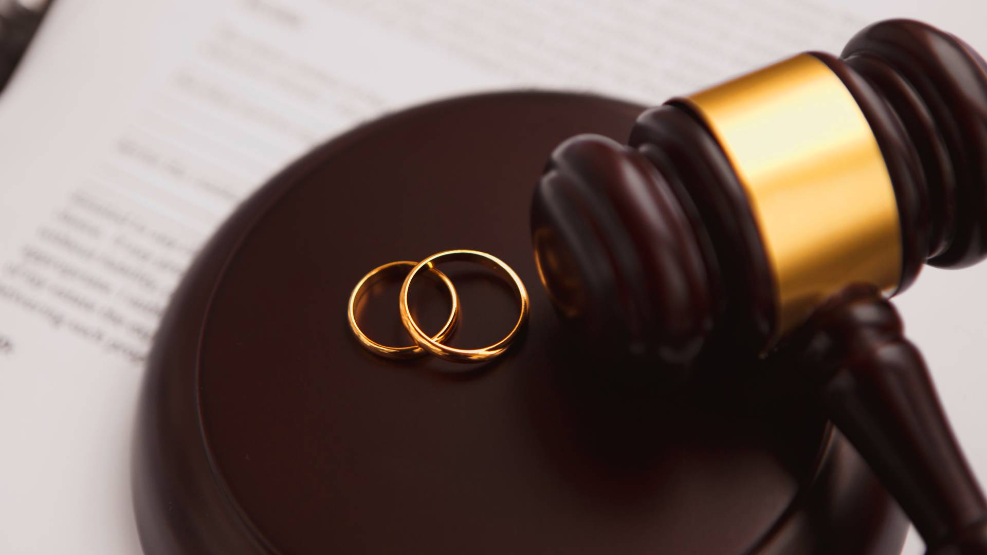 obrączki małżeńców obok młotka sędziego symbolizującego rozwód