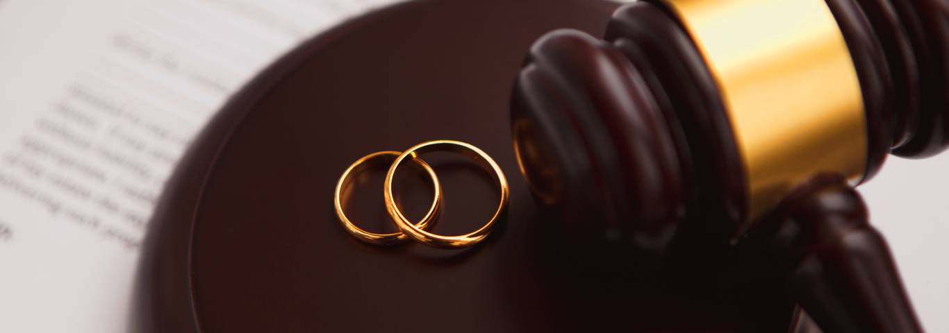 obrączki małżeńców obok młotka sędziego symbolizującego rozwód