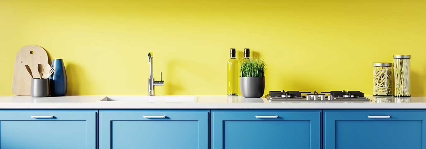 kuchnia z niebieskimi meblami i ścianą pomalowaną żółtą farbą zmywalną