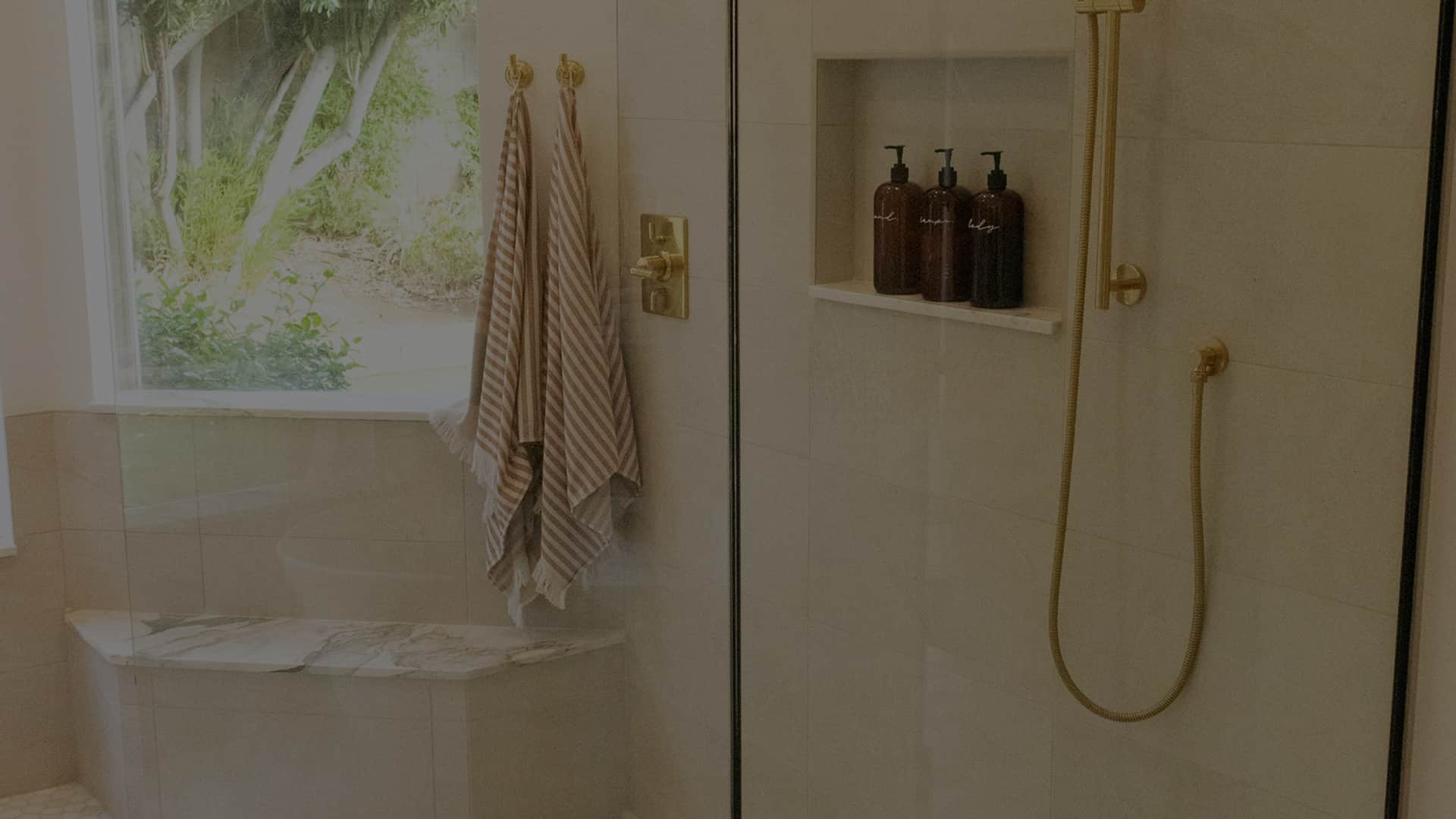 Elegancka łazienka z prysznicem i złotą armaturą z odpływem liniowym