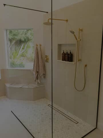 Elegancka łazienka z prysznicem i złotą armaturą z odpływem liniowym