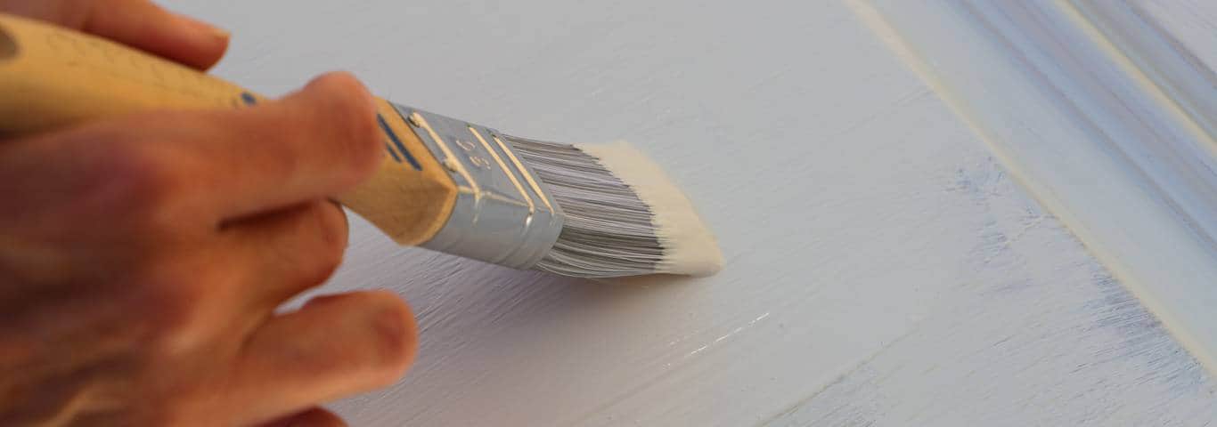 zbliżenie na pędzel malujący mebel na biało