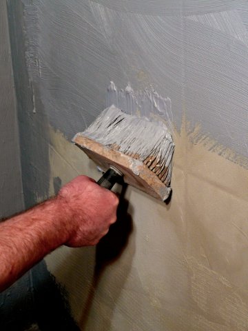 malarz maluje płytki w łazience farbą do malowania płytek