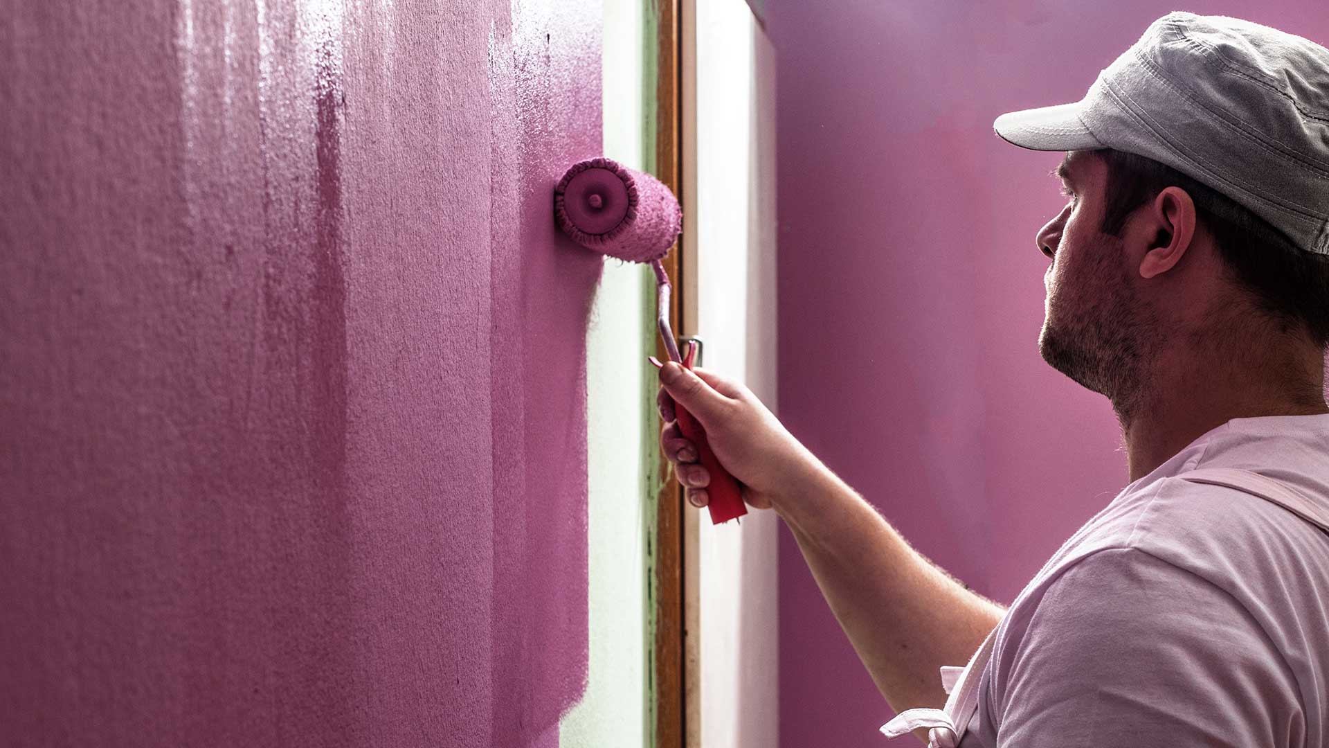 malarz maluje ściany na różowo wałkiem malarskim -  w 2022