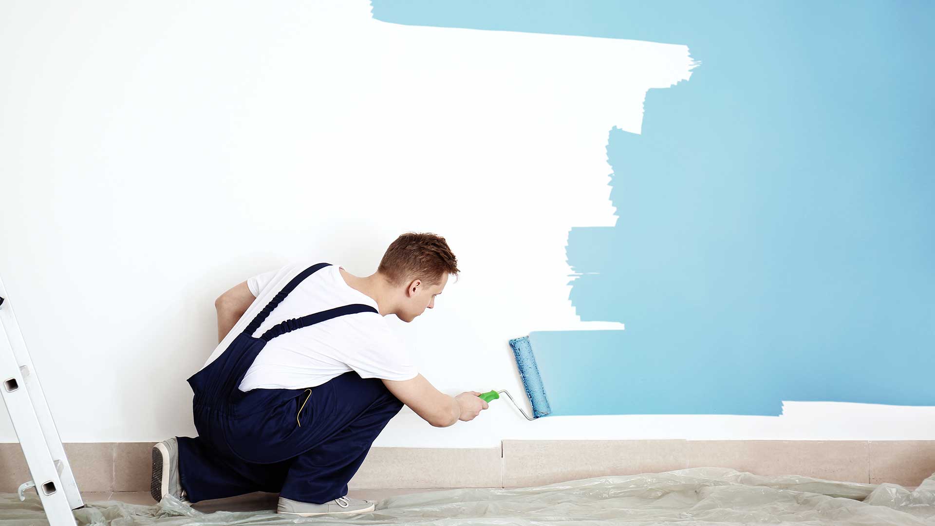 specjalista maluje ścianę wałkiem malarskim na niebieski kolor -  w 2021