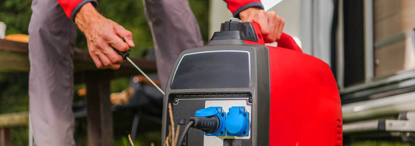 Mężczyzna odpala agregat prądotwórczy inwertorowy w ogrodzie – przenośny model z gniazdkami 230V