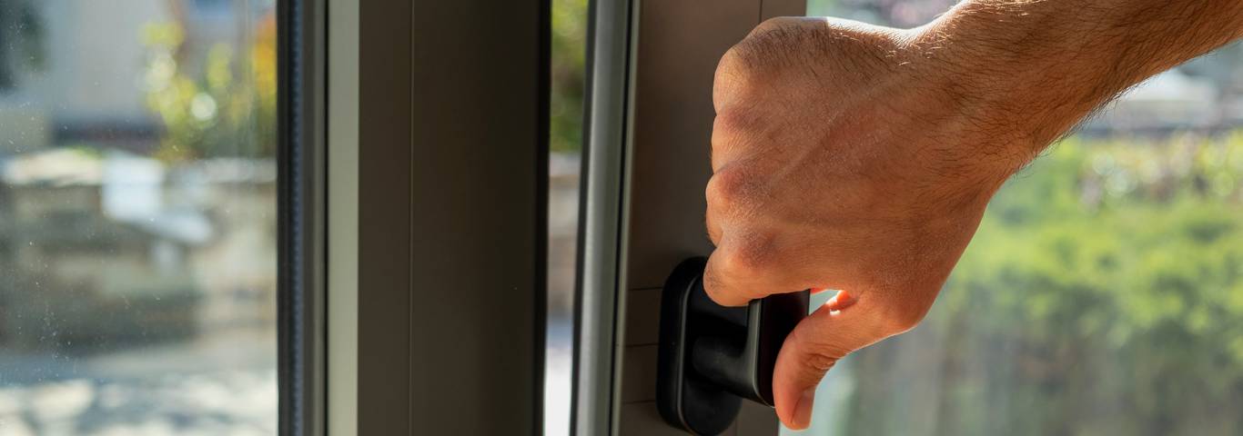 zbliżenie na rękę mężczyzny otwierającą okno aluminiowe