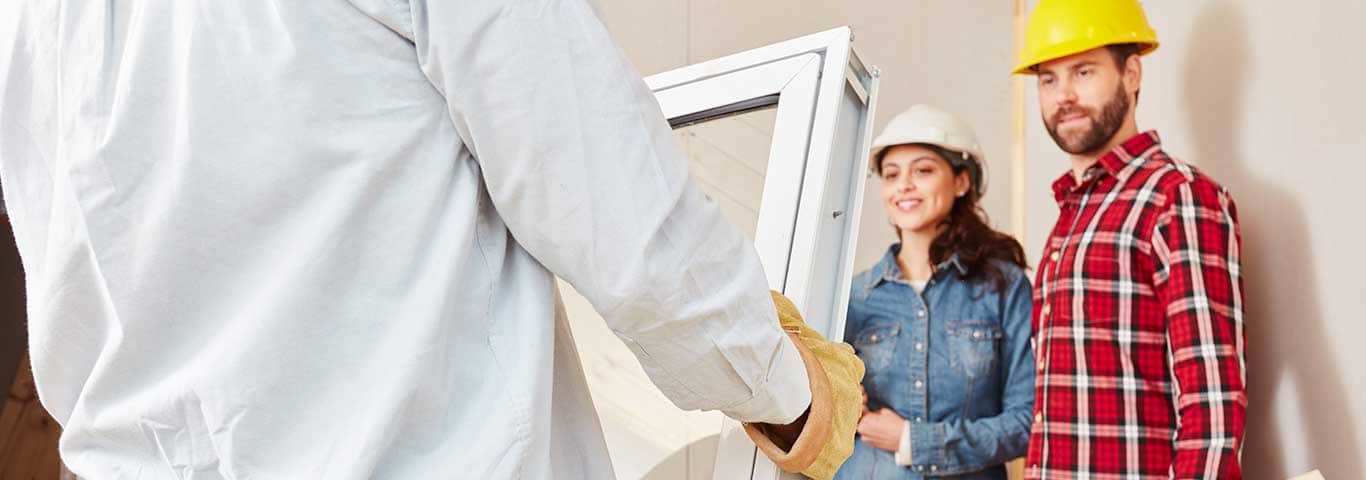 mężczyzna i kobieta patrzą na fachowca trzymającego okno PCV