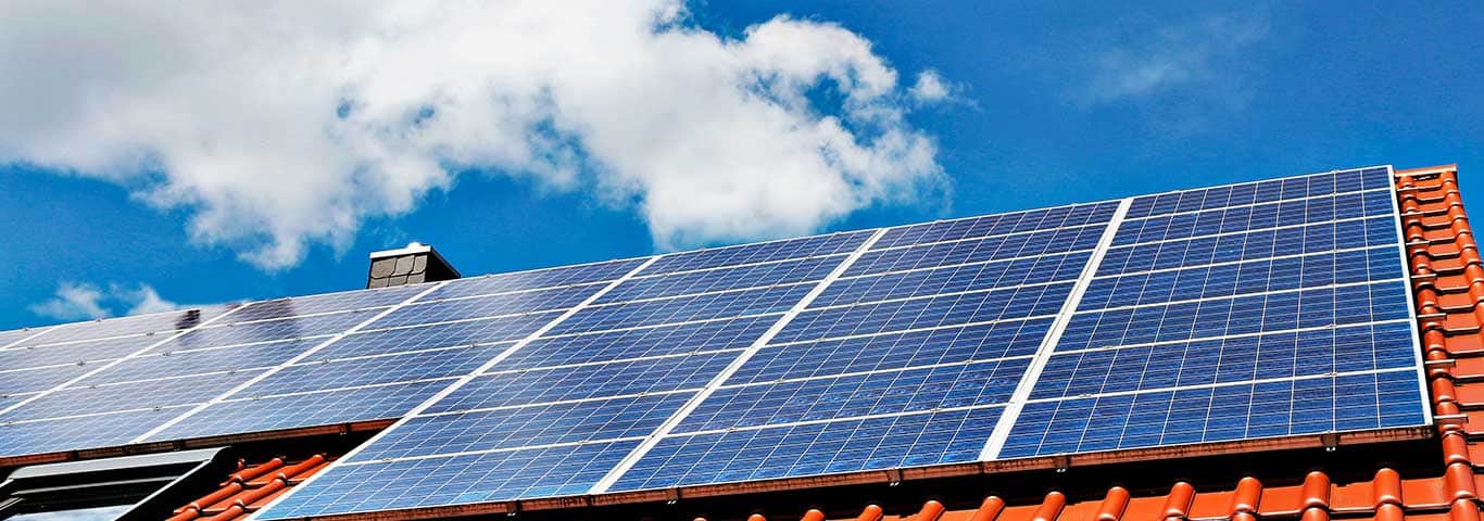 Panele fotowoltaiczne zamontowane na skośnym dachu domu jednorodzinnego w słoneczny dzień