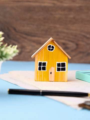 Model domu z monetami i dokumentami jako symbol inwestycji w fotowoltaikę z magazynem energii