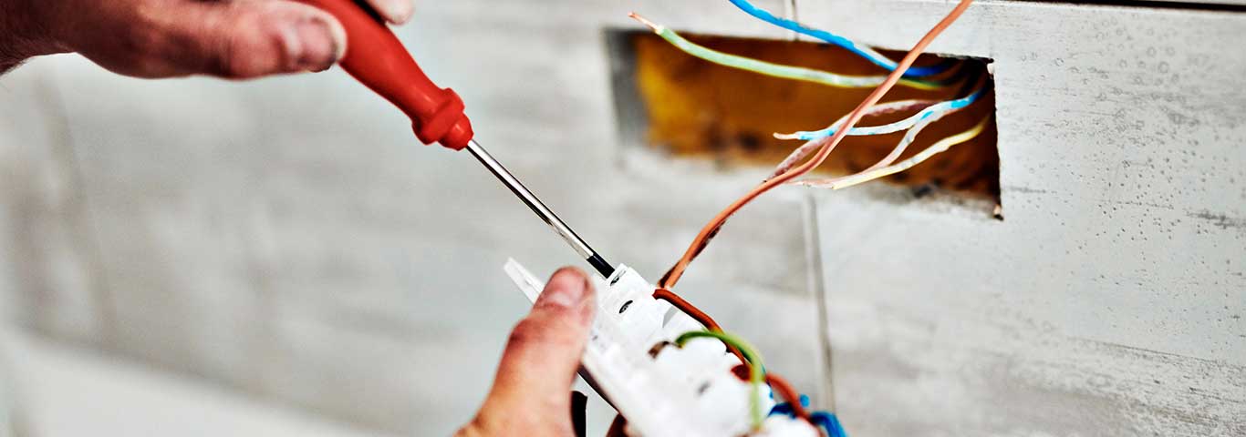 elektryk podpina do gniazdka kable elektryczne w odpowiednim kolorze