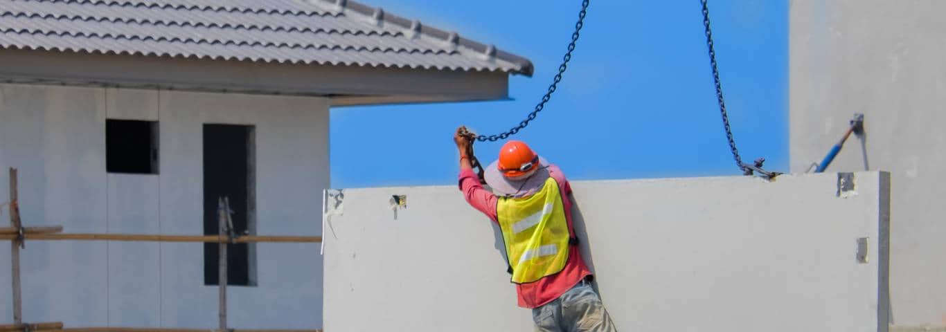 pracownik instaluje ścianę domu z prefabrykatów