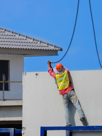 pracownik instaluje ścianę domu z prefabrykatów