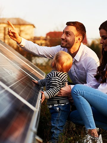 Rodzina z dzieckiem przy panelach fotowoltaicznych w kontekście wyboru magazynu energii