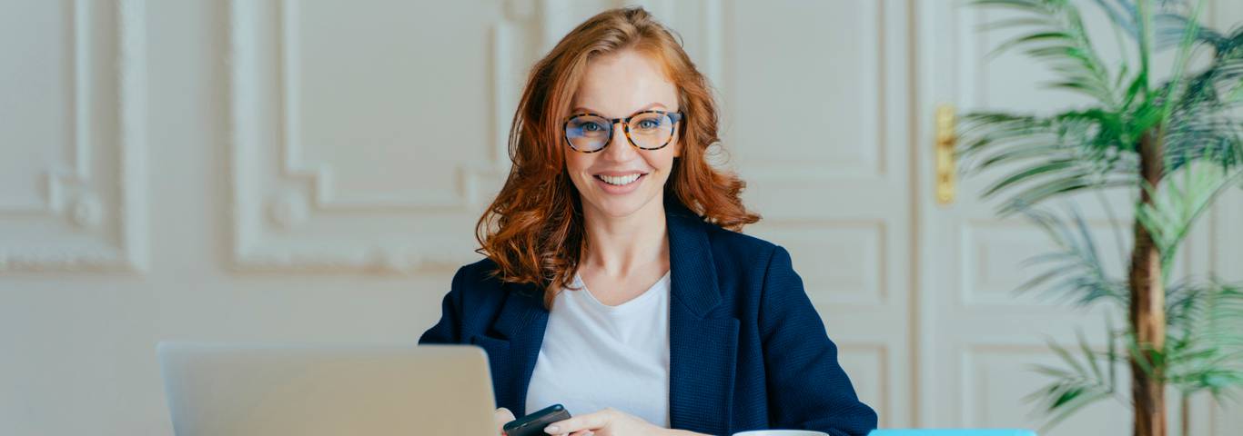 rudowłosa kobieta zatrudniona w ramach leasingu pracowniczego siedzi przy biurku