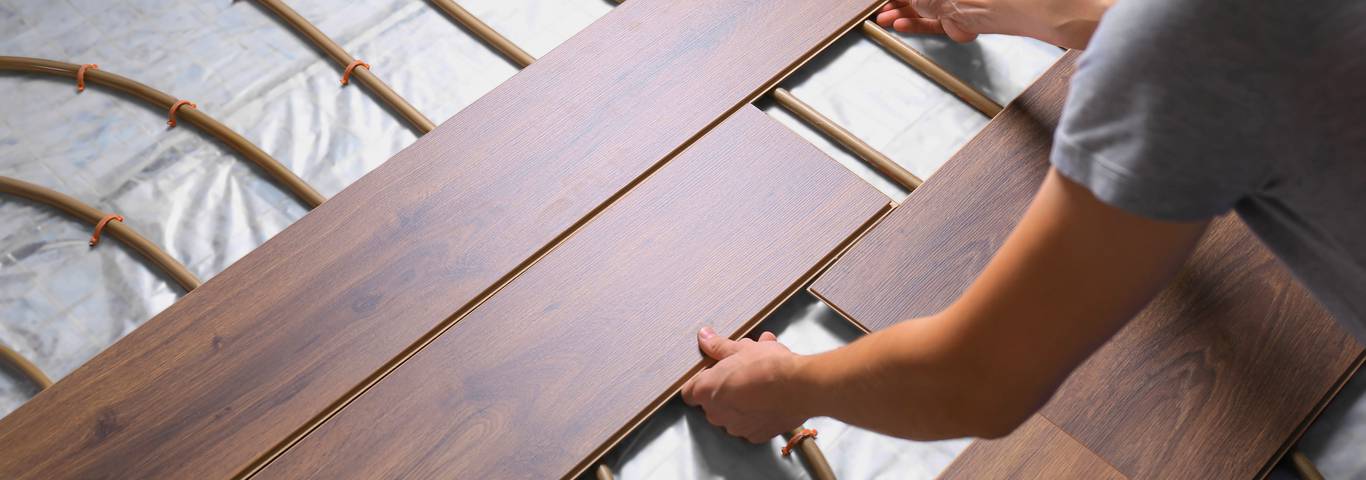 specjalista układa deski drewniane na ogrzewaniu podłogowym